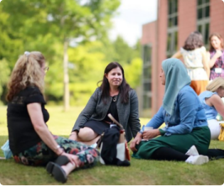 An image of team members sitting outside on the grass